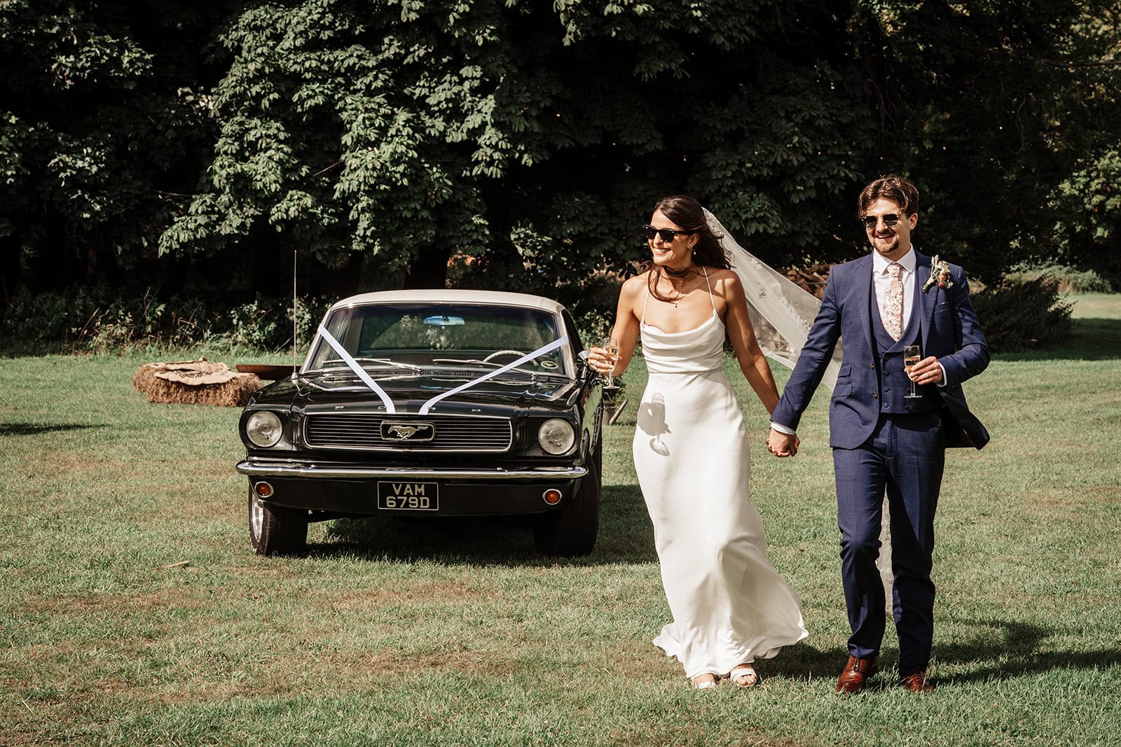 Bride and groom walking with vintage car