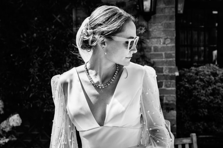 Bride wearing sunglasses walking in elegant gown