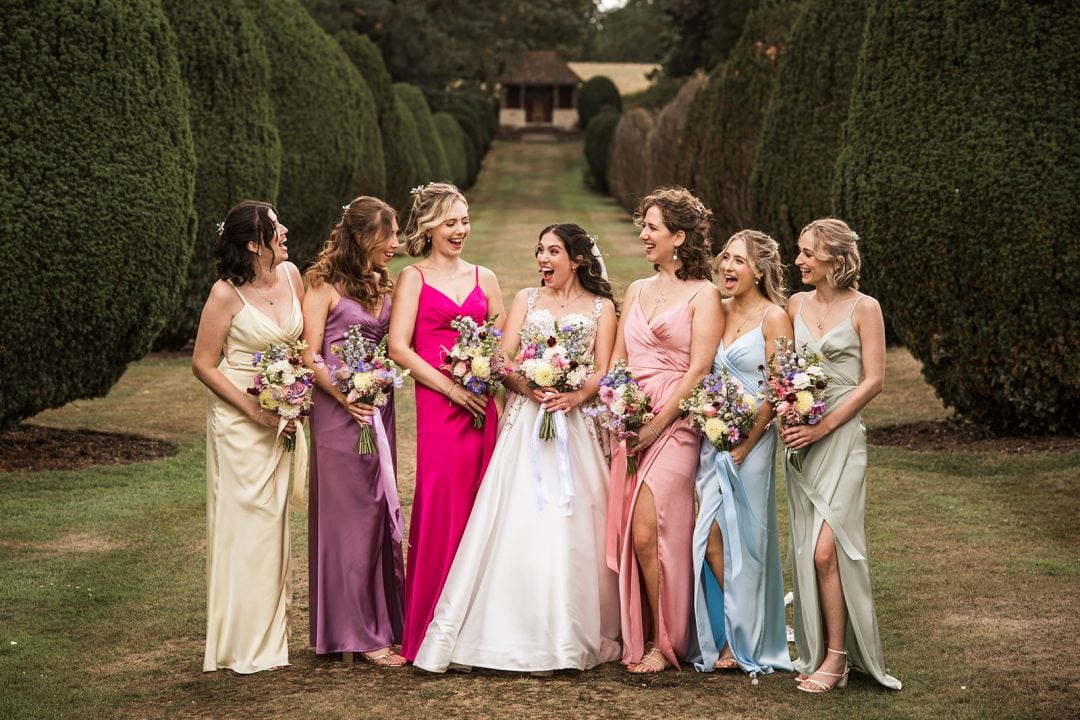 Beautiful bridal party walking together in vibrant dresses during outdoor wedding at The Elvetham
